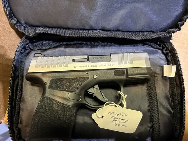 Springfield Armory Hellcat 9mm handgun with silver slide inside a black padded carrying case.