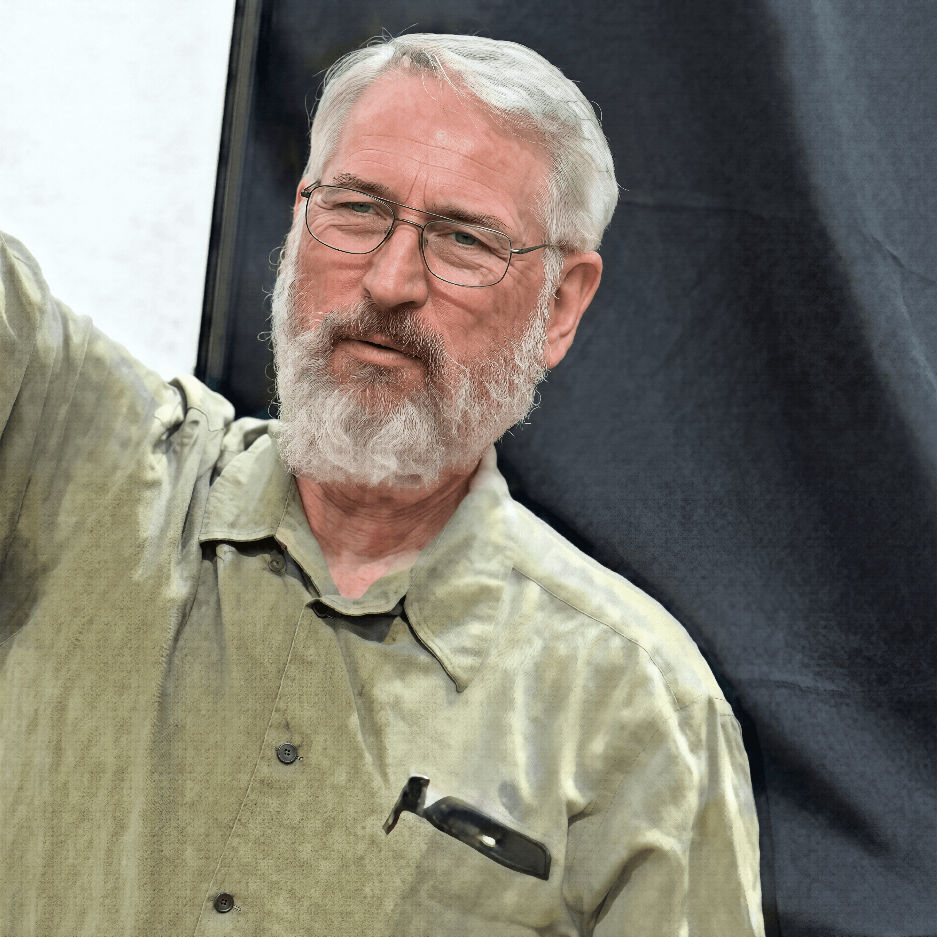 Older man with white hair and beard, wearing glasses and an olive-green button-down shirt.