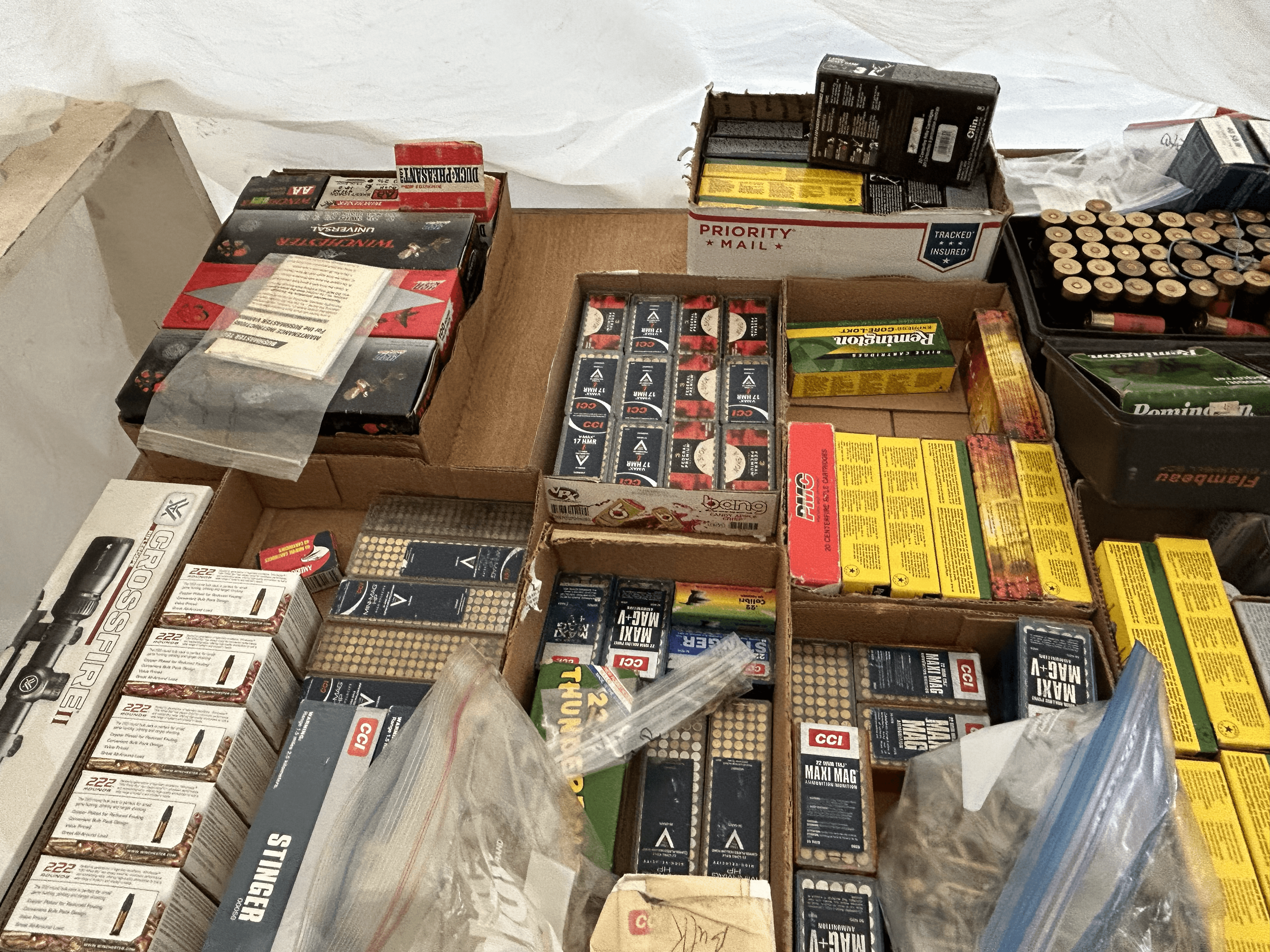 Assorted ammunition boxes, loose shells, and a rifle scope packed into several cardboard boxes.