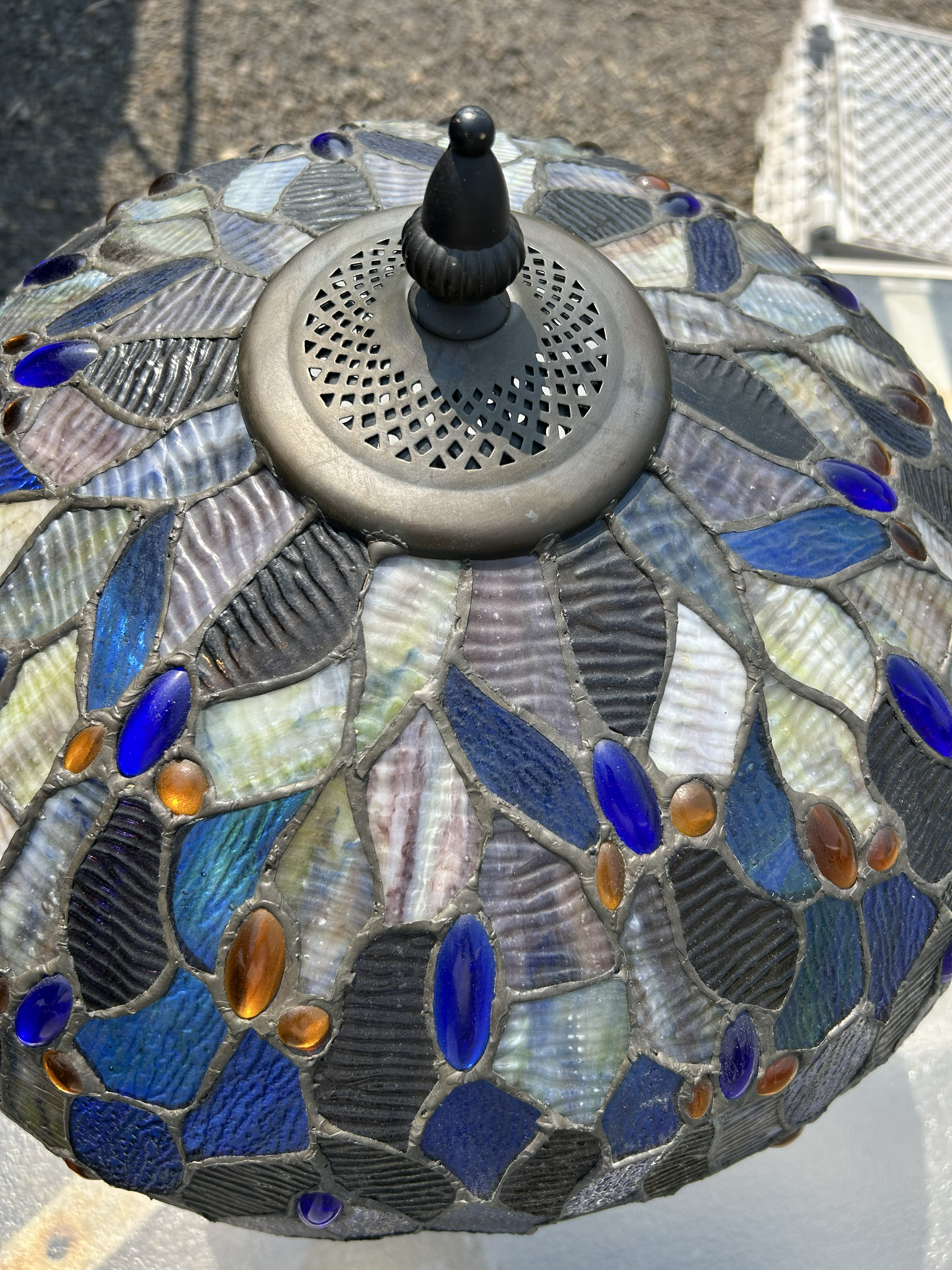 Close-up of a Tiffany-style lampshade with blue, grey, and amber stained glass mosaic pieces.