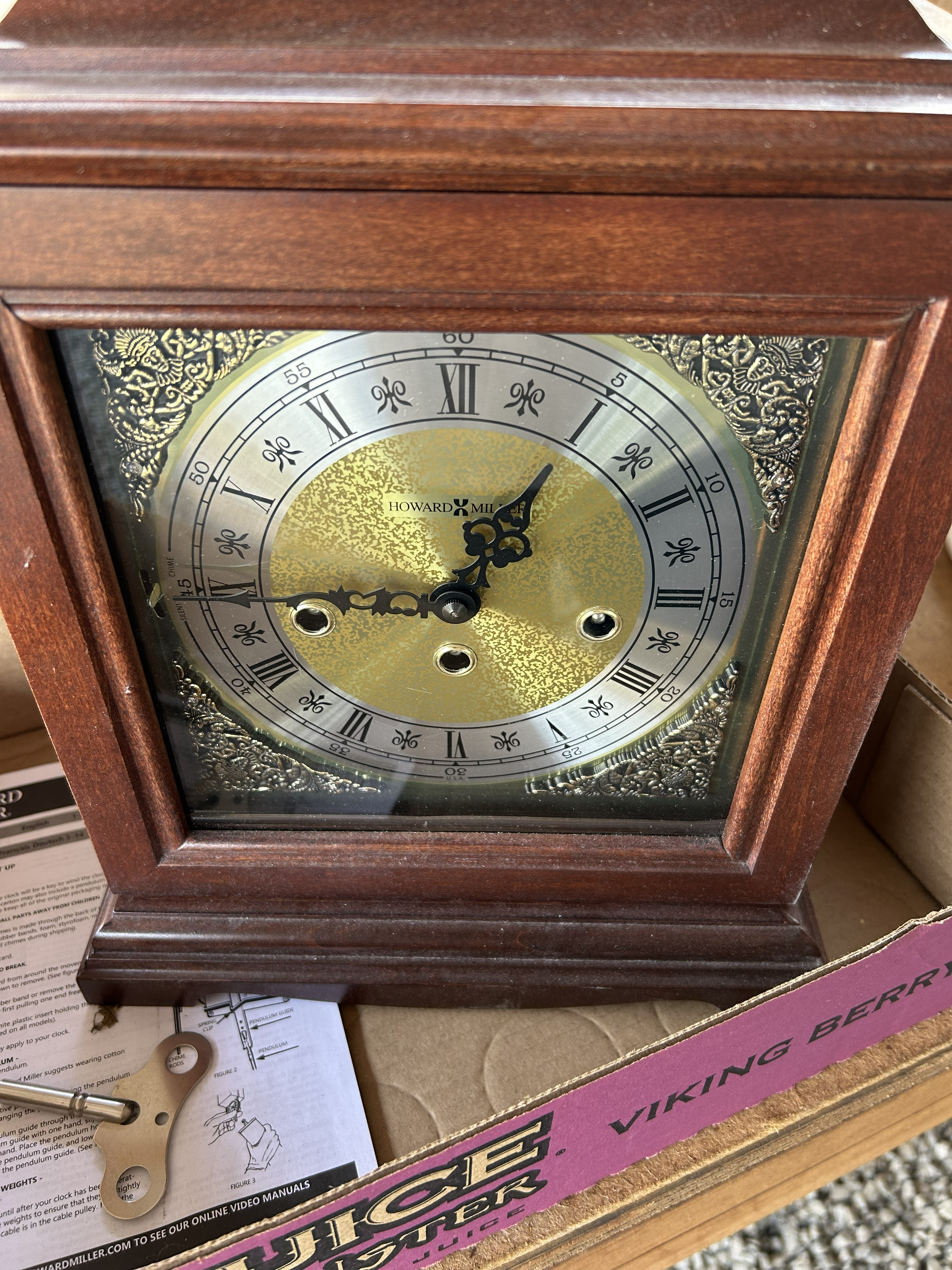 Howard Miller wooden mantel clock with a silver Roman numeral dial and gold textured center.